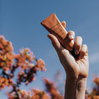 Absolution Le Masque Riche Réconfortant in a brown tube against a blue sky, skin care