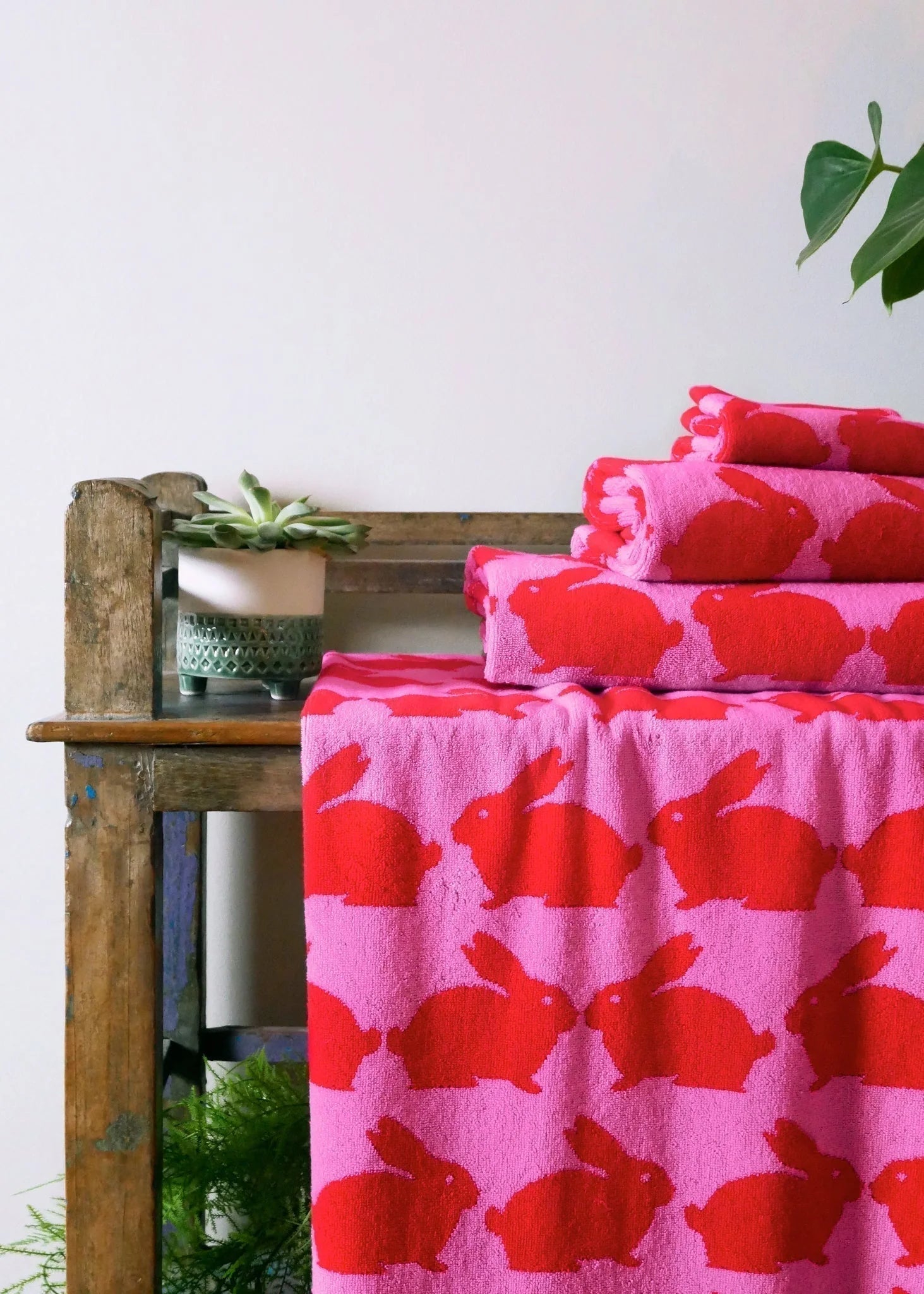 Kissing Rabbits Organic Cotton Beach Towel – pink with red bunnies, on wooden bench, white background – beach accessories