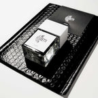 Je Ne Regrette Rien Parfum – quadratische Glasflasche mit weißem Deckel, schwarzer Hintergrund – Parfüm