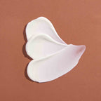 White texture of Le Masque Riche Réconfortant on a brown background, luxury skin care