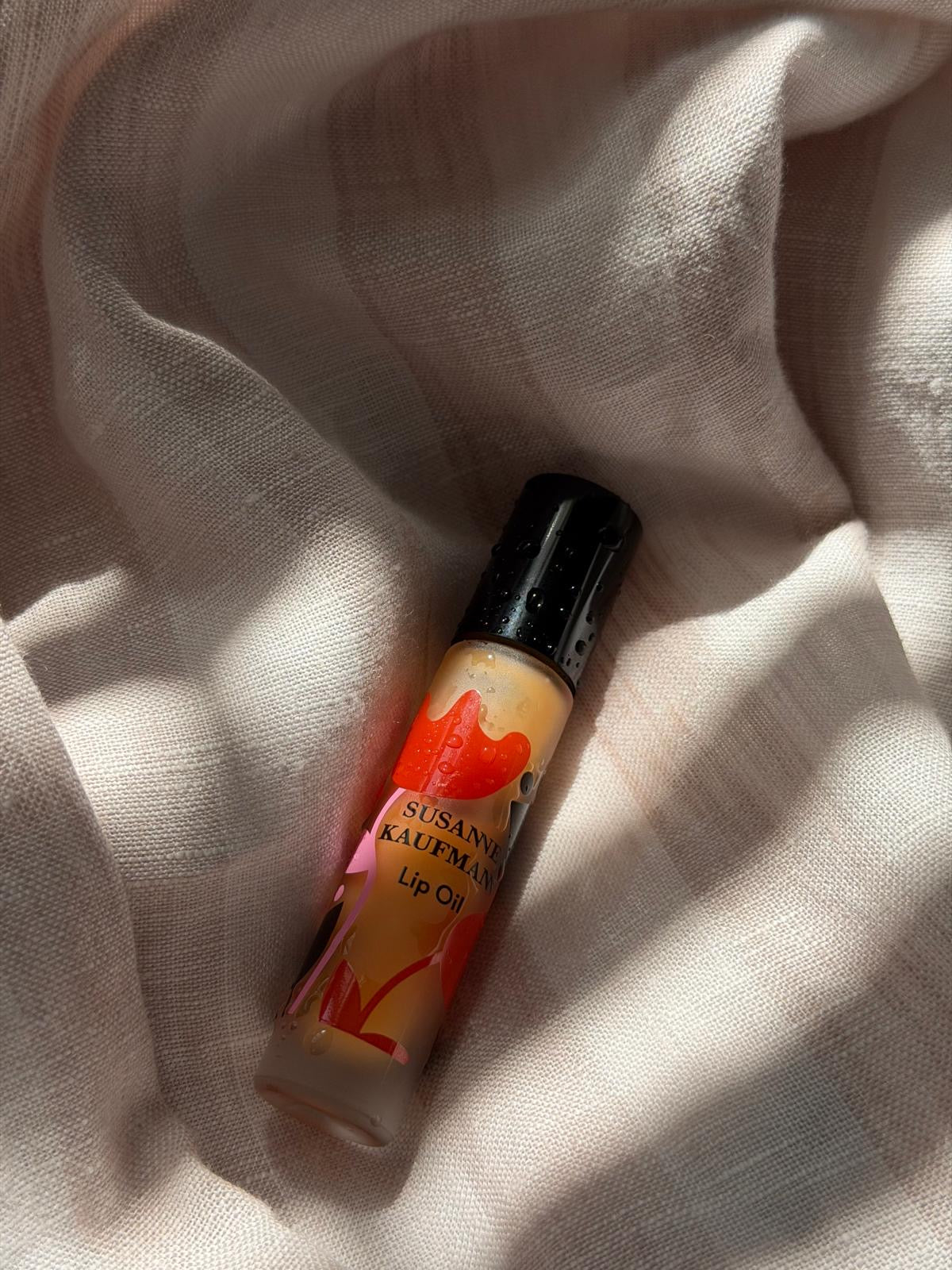 Susanne Kaufman Lip Oil auf hellem Stoff, Lippenpflege.
