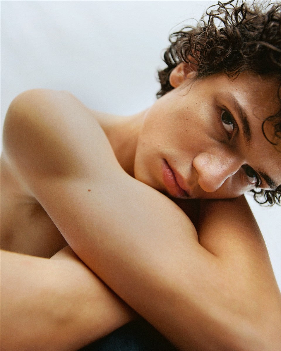 No product image – portrait of person with curly hair on light background – skin care