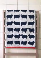 Sheep Organic Cotton Waschlappen – grau mit schwarzen Schafen, roter Saum, auf Heizkörper – Gesichtspflege