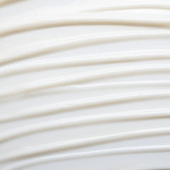 Texture of white Chamomile Cleansing Milk on a light background, gentle skin care