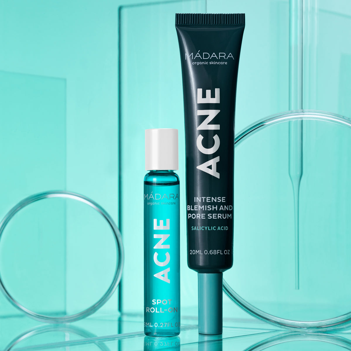 Mádara Acne Acute Spot Roll-on in einer blauen Glasflasche mit weißem Verschluss neben einer Tube.