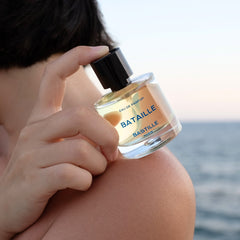Bataille Eau de Parfum – klares Glasflakon mit schwarzem Verschluss, blauer Schrift, Meereskulisse – Parfüm