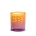 Farbenfrohe NEOM Wellbeing Duftkerze in einem orange-violetten Glas auf weißem Hintergrund.