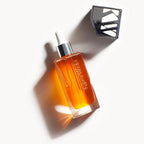 The Beautiful Oil Travel – clear glass bottle with dropper, golden oil, white background – skin care