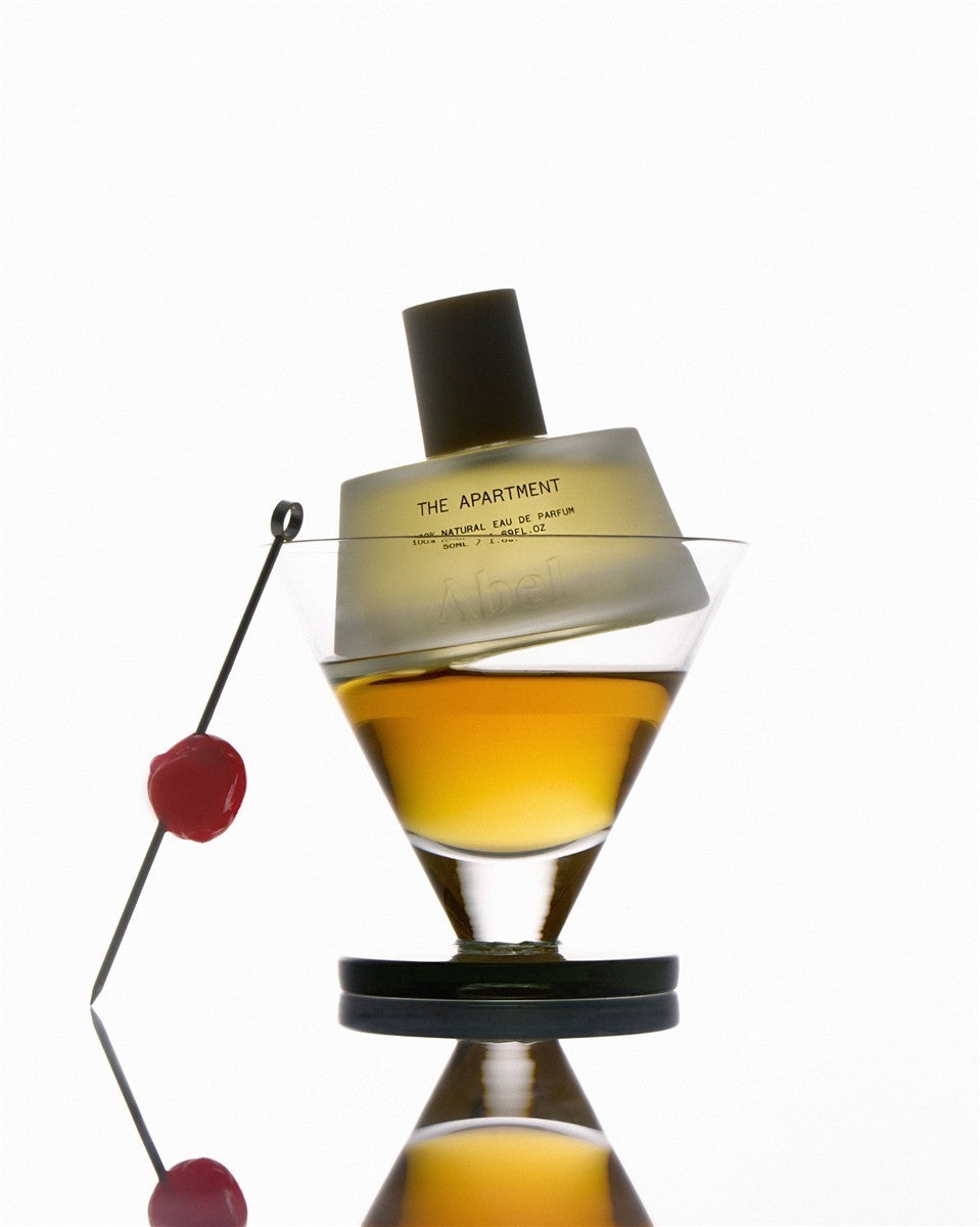 The Apartment Mini Parfümset Warm – goldfarbenes Eau de Parfum in Glasflasche mit schwarzem Verschluss, weißer Hintergrund – Parfüm