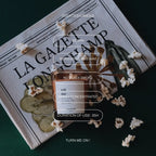 Eat Me scented candle in a brown glass jar on a newspaper, vegan wax for a fragrant home ambiance.
