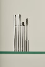 Holi(lash) Growth Mascara – silberne Tube mit geöffnetem Deckel, Wimpernbürste, cremefarbener Hintergrund – Wimpernpflege