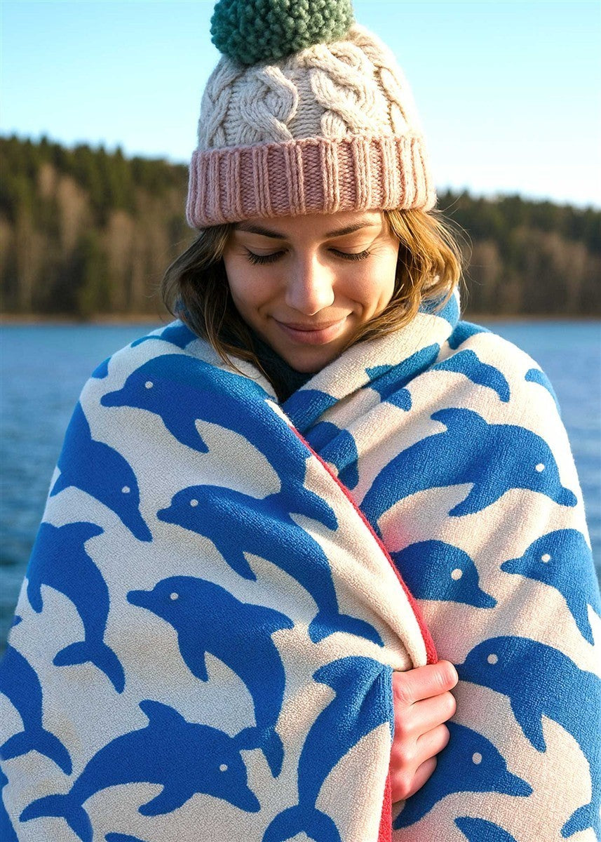 Jumping Dolphins Baumwollhandtuch – blau-weißes Delfinmuster, Frau am See – Wellness & Entspannung