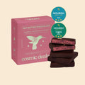 Cosmic Dealer Nut Butter Chocolate Raspberry & Macadamia in pinker Box auf beigem Hintergrund, vegane Süßigkeit.