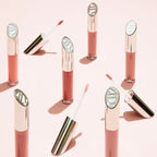 Multiple Lip Gloss Fascination glass tubes with silver caps on a pink background, glossy makeup.