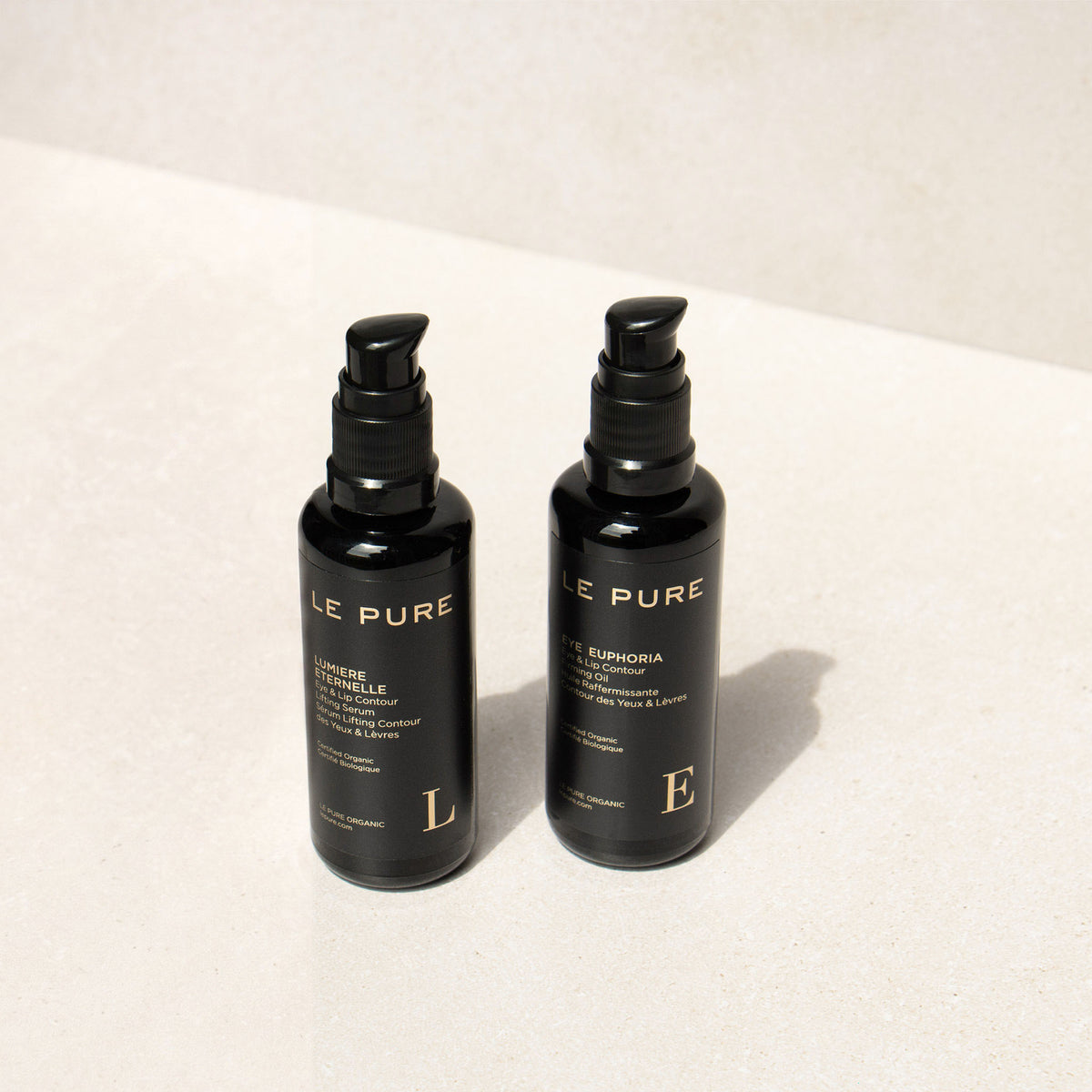 Le Pure E&l the Eye Set: zwei schwarze Flaschen mit Pumpaufsatz auf hellem Hintergrund, Augenpflege.
