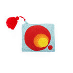 Clutch Pequeño Degradado, eine kleine hellblaue Perlenclutch mit einem rot-gelben Kreisdesign und einer roten Quaste.
