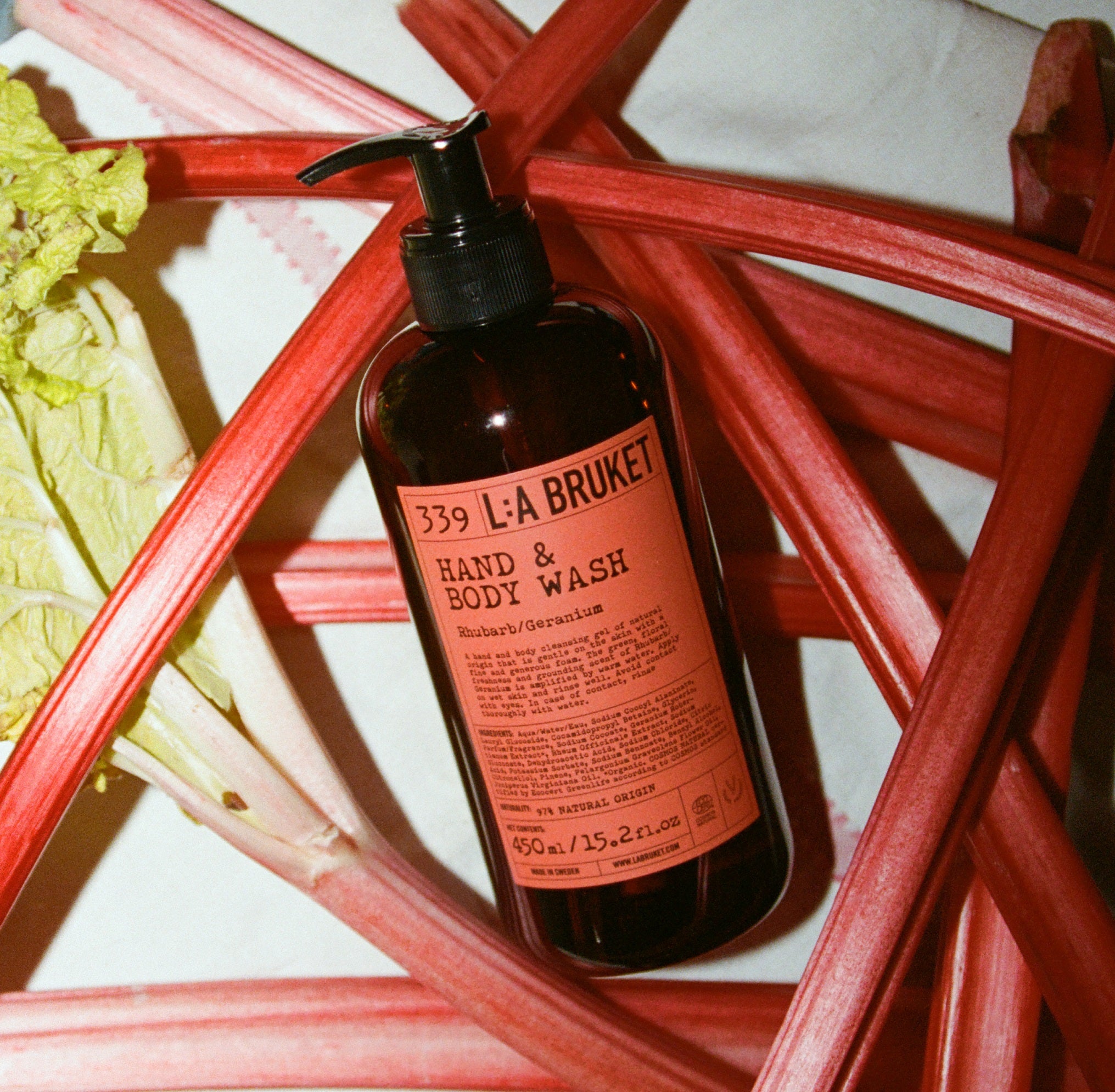 L:A Bruket No. 339 Hand & Body Wash, braune Flasche, rotes Etikett, umgeben von Rabarber