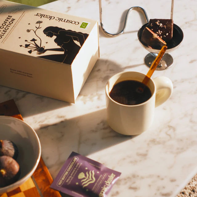 Cosmic Dealer I Quit Coffee Collection – beige Kartonbox mit schwarzer Silhouette, lila Beutel, Marmorhintergrund – Beauty