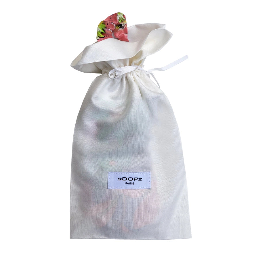 Le Flora Maske in einem weißen Stoffbeutel mit Kordelzug.