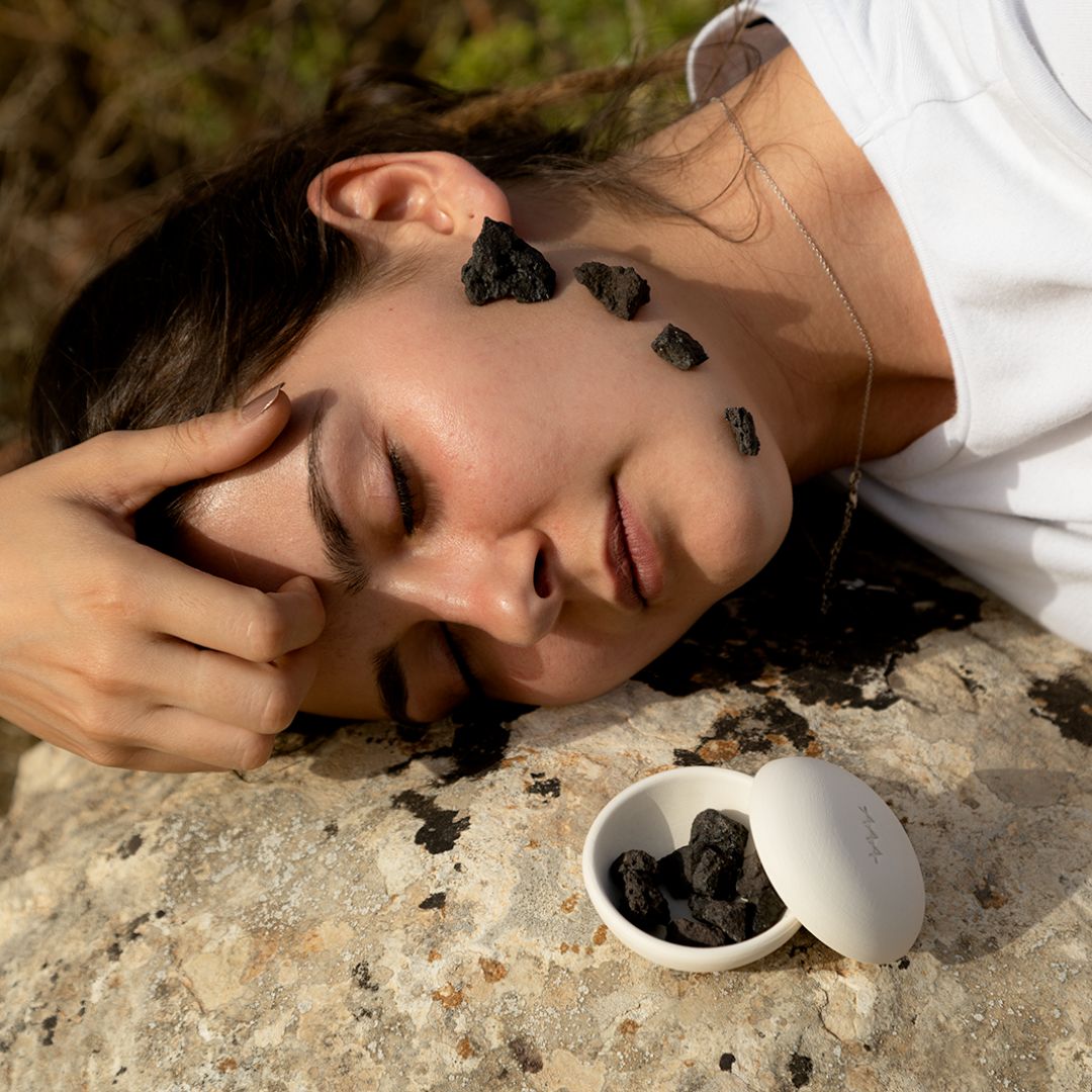 Scia Face Care – white ceramic container with lid, black stones, natural background – skin care