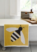 Buzzy Bee Bio-Baumwollwaschlappen – gelb mit Bienenmotiv, weißer Rand, auf Badewanne – Hautpflege