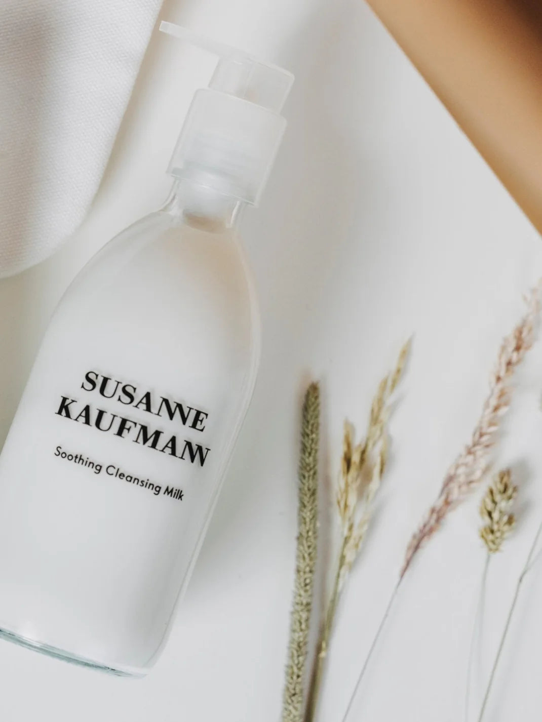 Weiße Susanne Kaufman Pflegende Reinigungsmilch in einer Flasche mit Pumpspender auf weißem Grund, Hautpflege. Moodbild