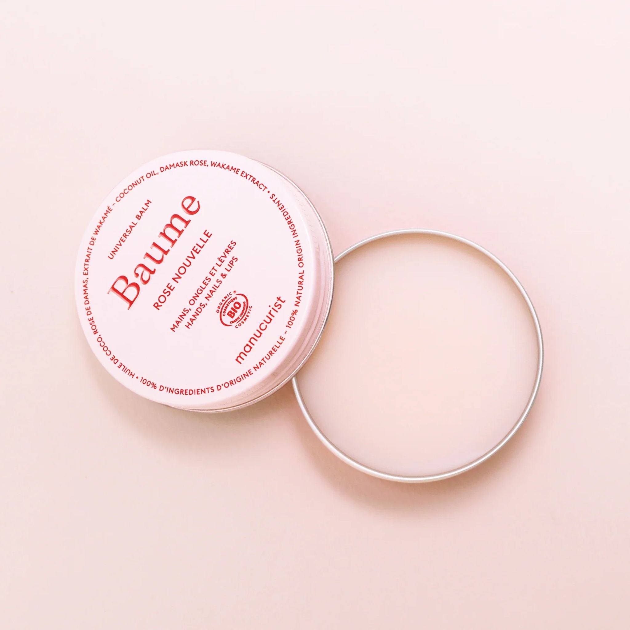 Baume Rose Nouvelle in a pink tin with an open silver lid on a pink background, skin care