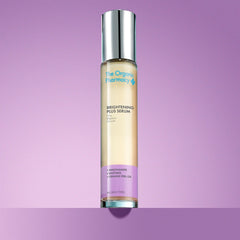 The Organic Pharmacy Brightening Plus Serum in a bottle with silver cap on a purple background, skin care mood
