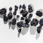 Scia – black volcanic rock pieces on white background – skin care