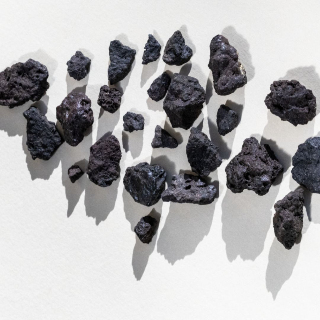 Scia – black volcanic rock pieces on white background – skin care