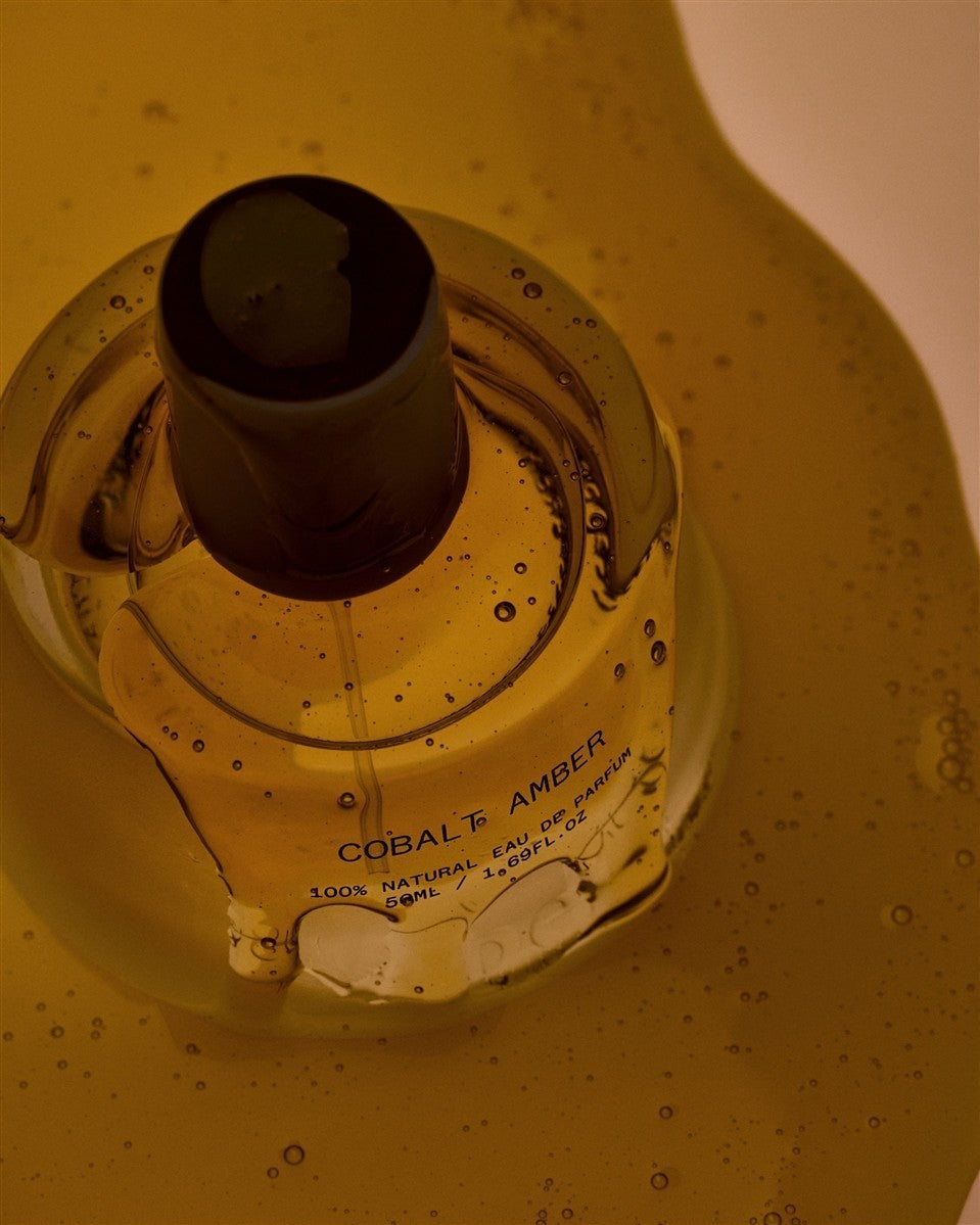 Cobalt Amber Eau de Parfum – transparente Glasflasche 50ml, schwarzer Verschluss, goldener Hintergrund – Parfüm