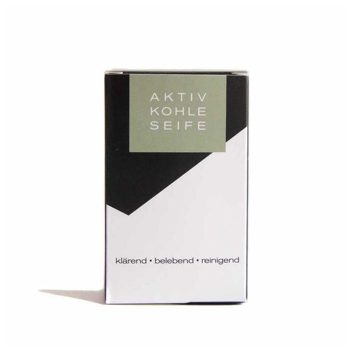 Aktivkohleseife – black and white cardboard packaging with olive green label, white background – skin care