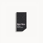 Kjaer Weis Lip Balm – schwarze Texturverpackung, weißer Hintergrund – Lippenpflege