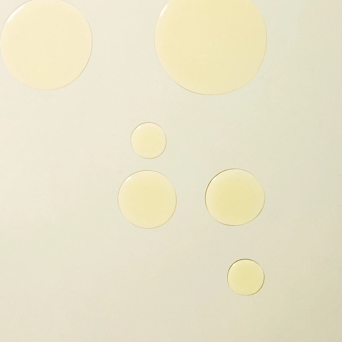 Holi(body) Ageless Body Sérum: Gelbe Serum-Tropfen auf hellem Hintergrund für die Hautpflege.