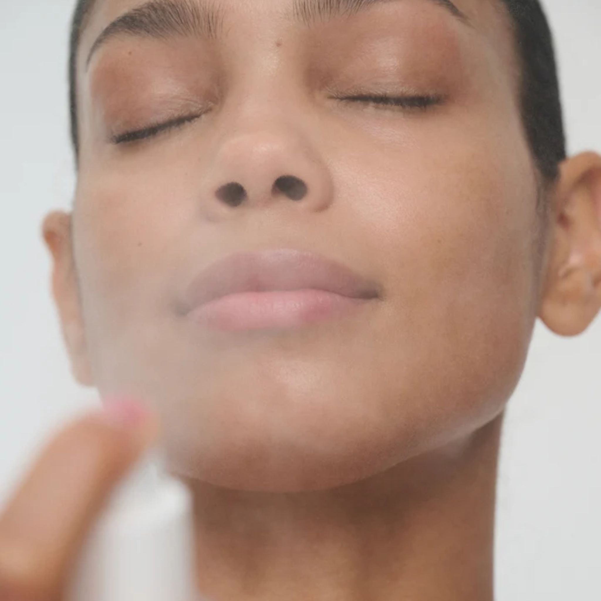 Woman using SuperSerum Hydrating Mist Travel spray for skin care on white background