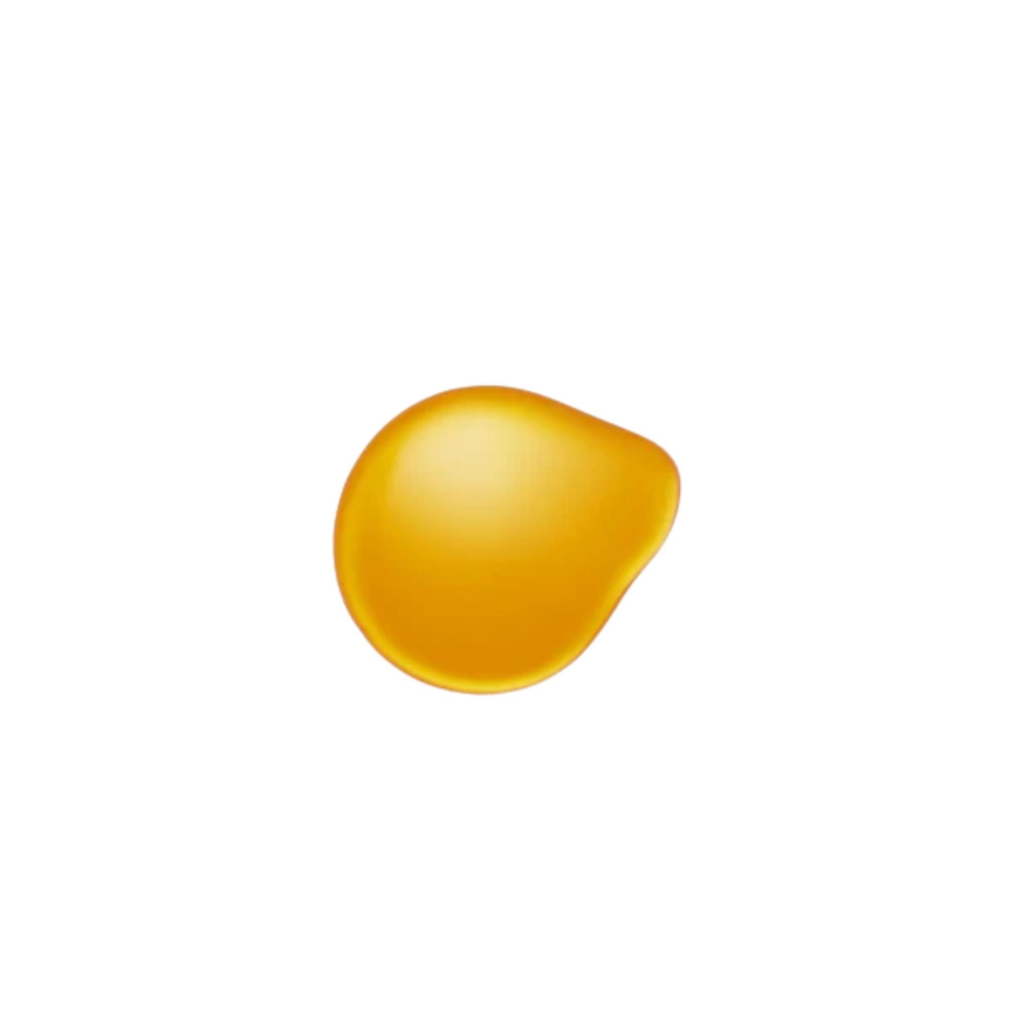 A golden yellow drop of Kakadu Beauty Body Oil on a white background for skin care