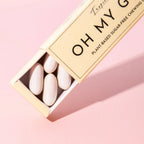 Oh My G Plant Based Chewing Gum Tropic in einer beigen Pappschachtel auf rosa Hintergrund, zuckerfreier Kaugummi.