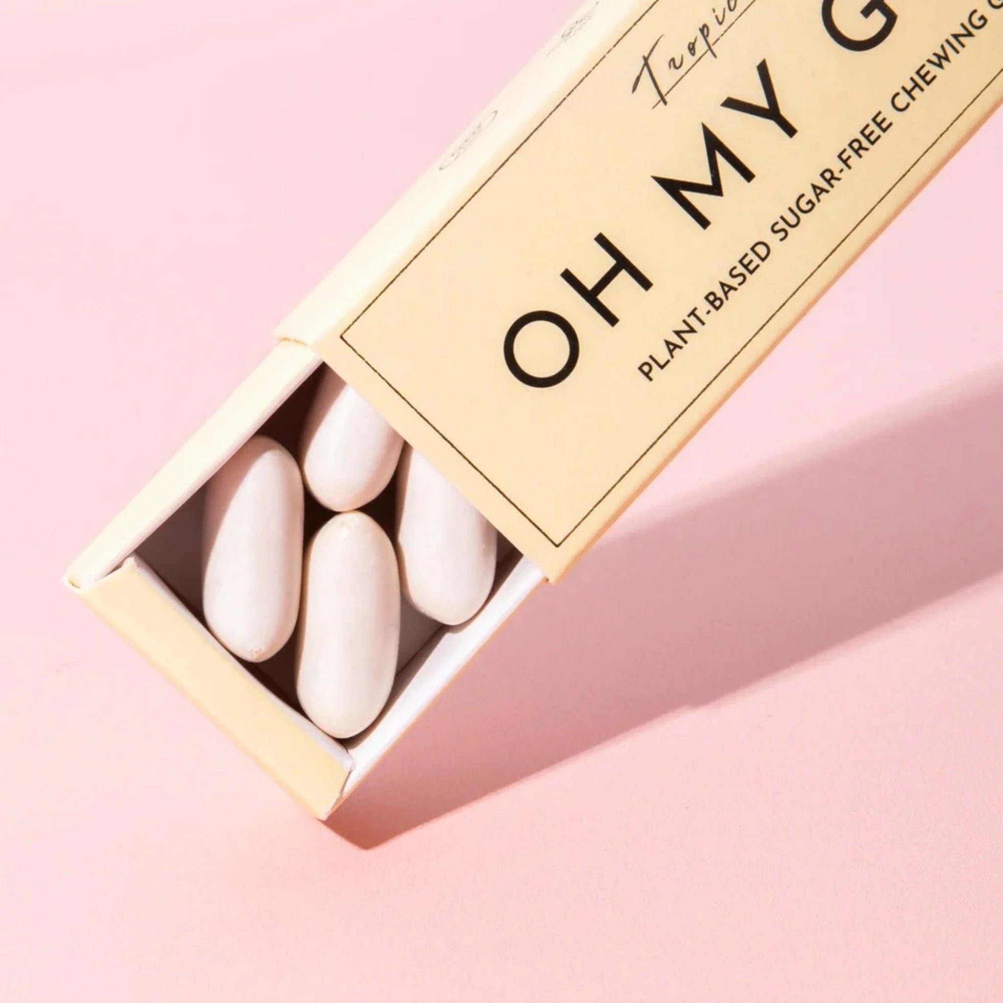 Oh My G Plant Based Chewing Gum Tropic in einer beigen Pappschachtel auf rosa Hintergrund, zuckerfreier Kaugummi.
