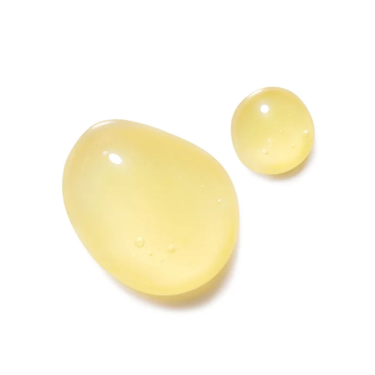 Two droplets of Regeneration Ölserum Intensiv in pale yellow on a white background, intensive skin care.