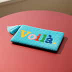Voilà Clutch, hellblaue, perlenbestickte Clutch mit farbigem Schriftzug auf rötlichem Hintergrund.